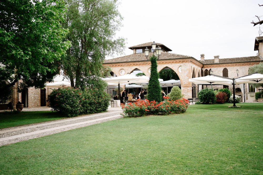 Elegant villa venue with manicured lawn, archways and outdoor seating areas surrounded by lush greenery.