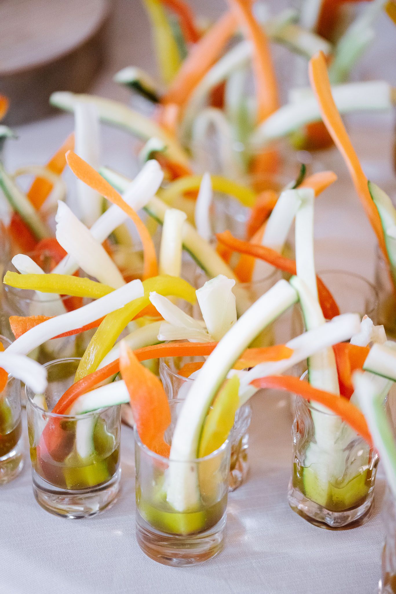 Colorful vegetable crudité appetizers arranged vertically in small glass cups.