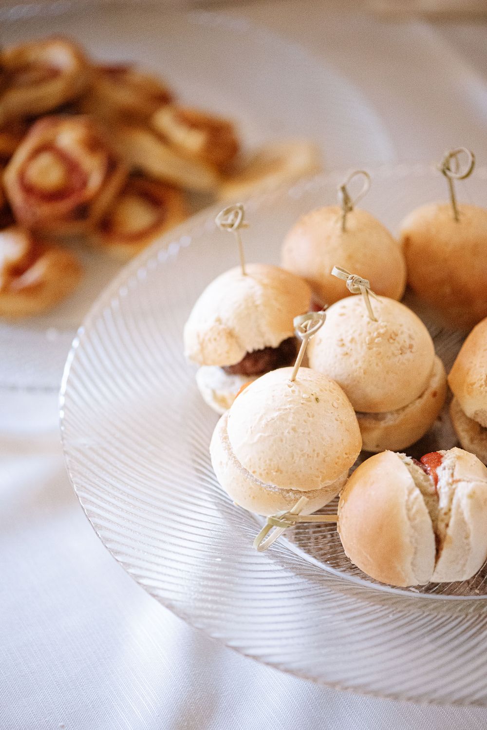 Mini sandwich sliders on toothpicks displayed on a crystal serving plate.