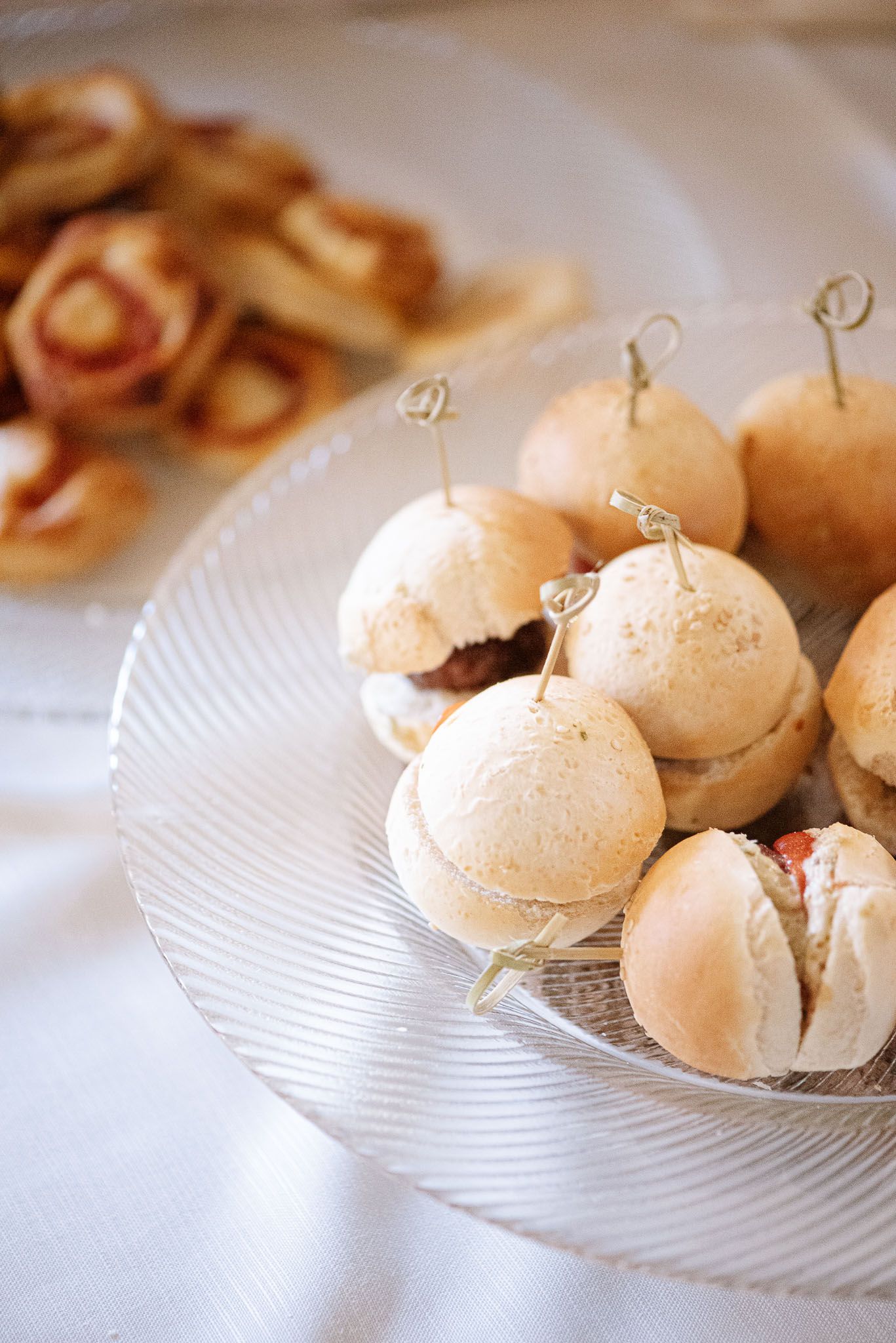 Mini sandwich sliders on toothpicks displayed on a crystal serving plate.