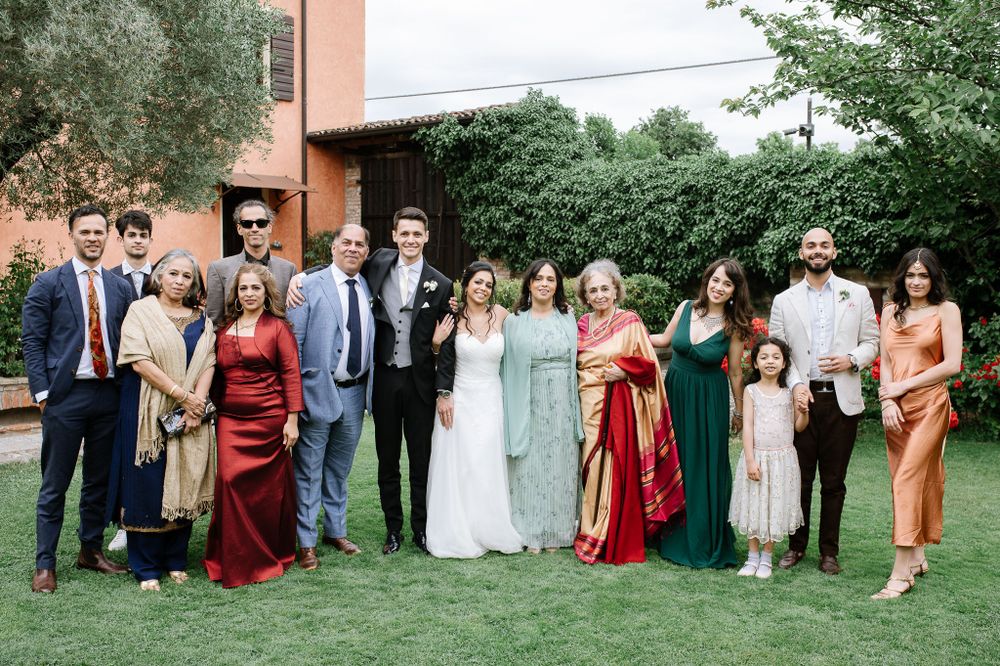 Wedding party photo showing group in colorful formal attire standing together on lawn.