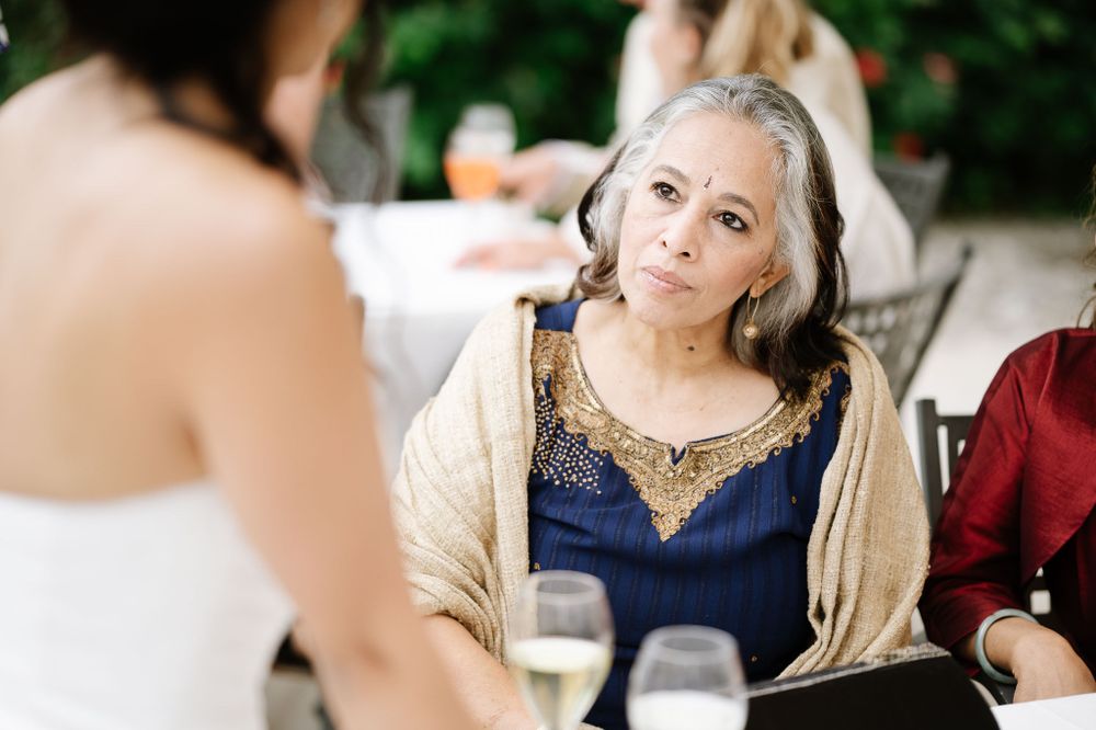 A dinner guest in evening wear engages in conversation at an elegant outdoor reception.