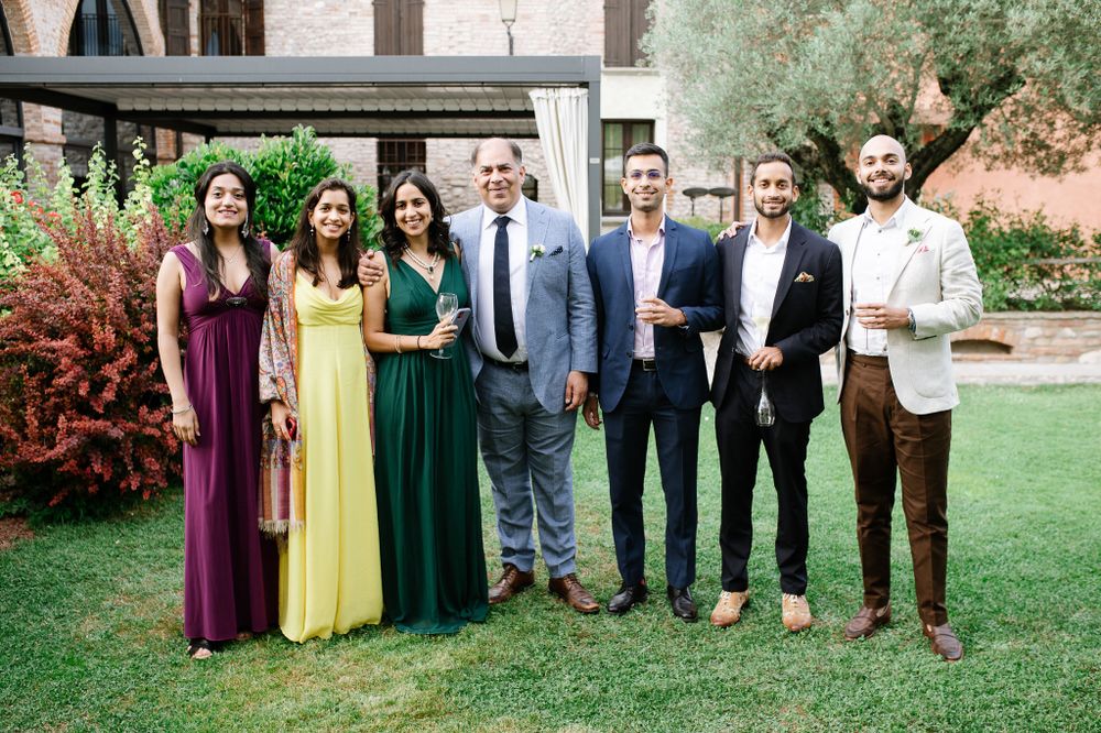 Wedding party members pose together outdoors wearing colorful formal attire.