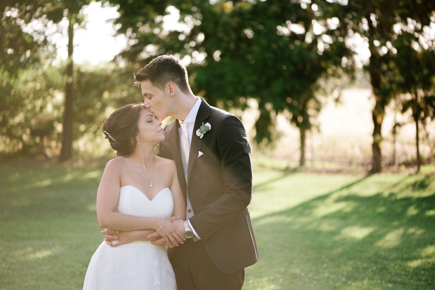 Intimate moment between newlyweds during outdoor sunset photo session.