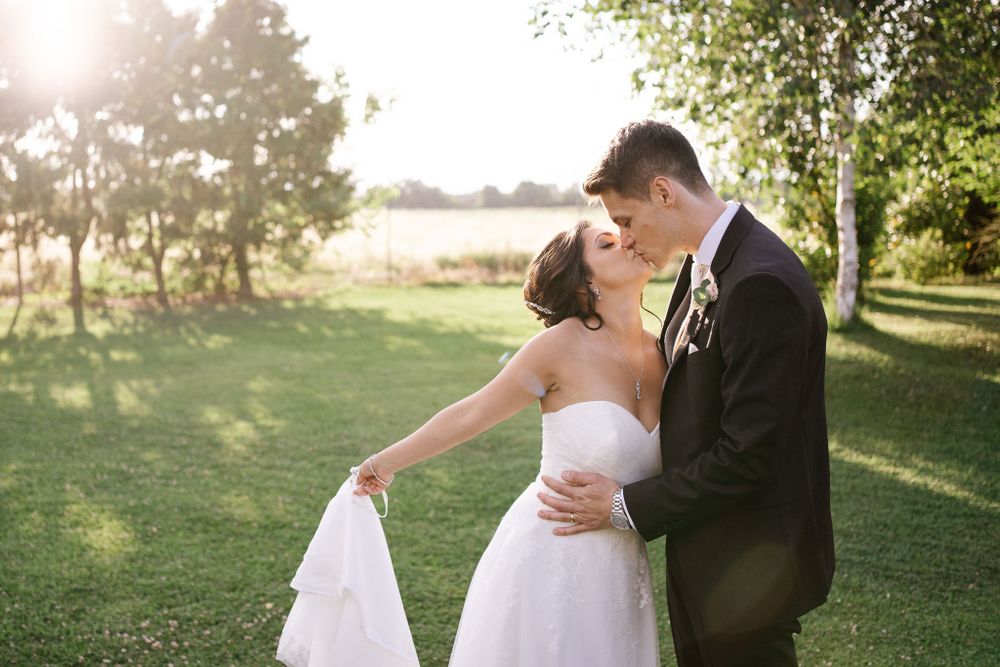 Newlyweds share a romantic moment on a grassy lawn during sunset.