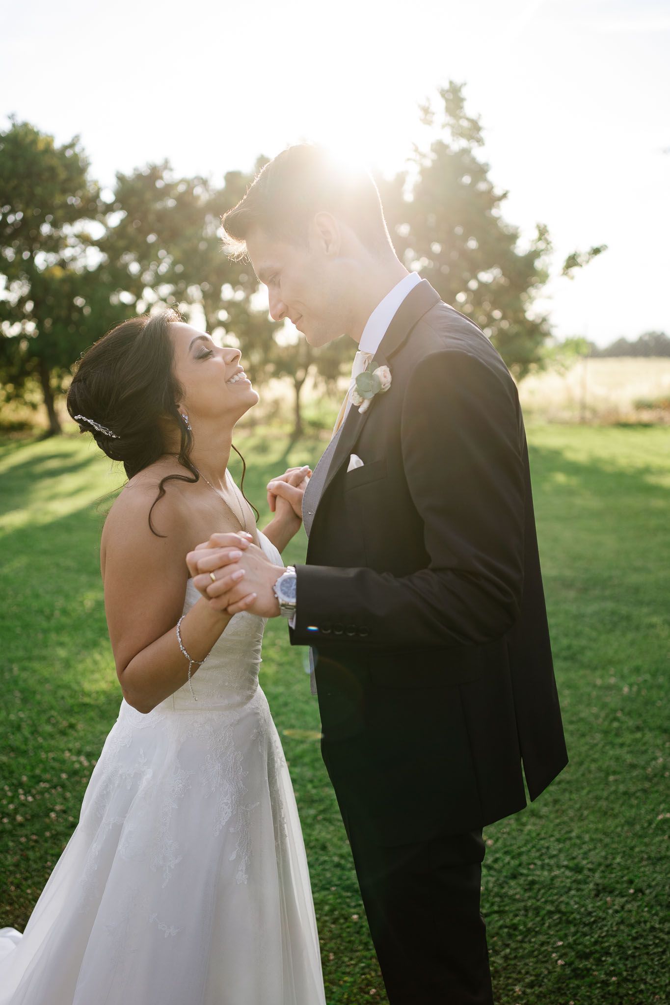 Romantic wedding portrait with golden sunset light filtering through trees.