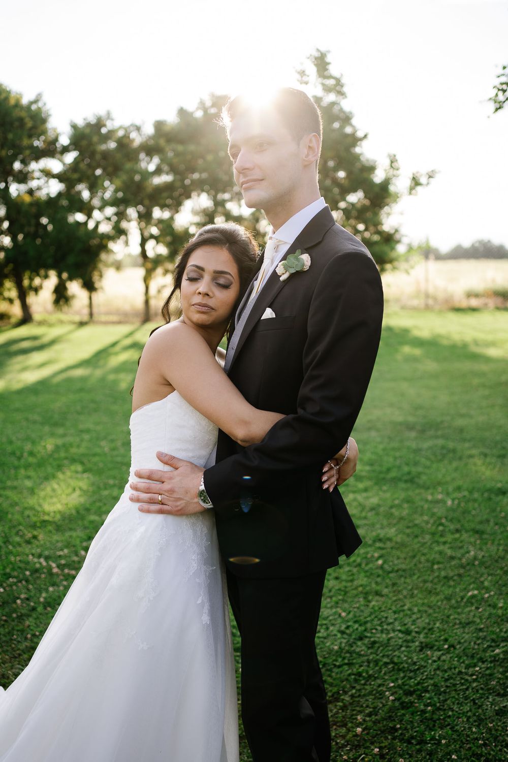 Intimate wedding portrait with couple embracing in late afternoon sunlight.