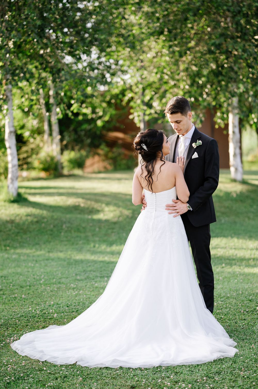 Wedding portrait showing elegant white dress train against green garden backdrop.