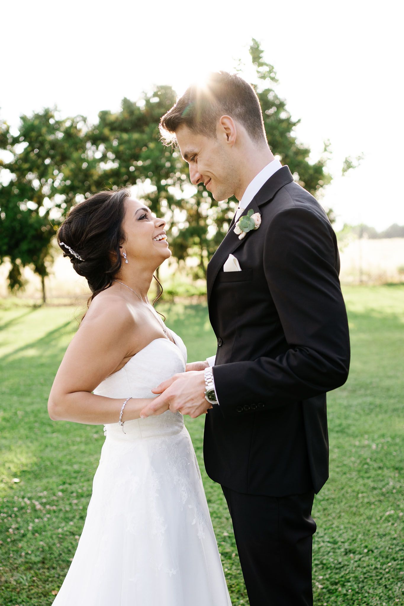 Candid wedding moment captured between couple on sunny lawn.