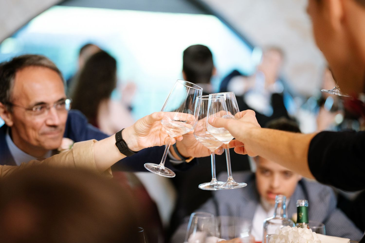 Wedding guests raise champagne glasses in a celebratory toast at reception.
