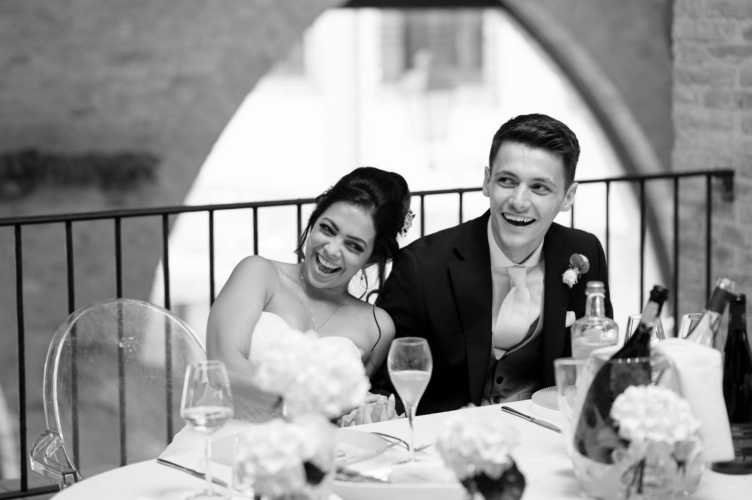 Candid moment of joy captured during wedding reception at elegant venue with stone archways.