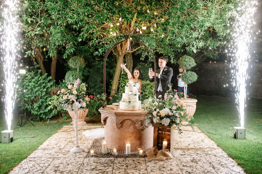 Wedding cake display with dramatic water fountains and lush garden decor creating romantic atmosphere.