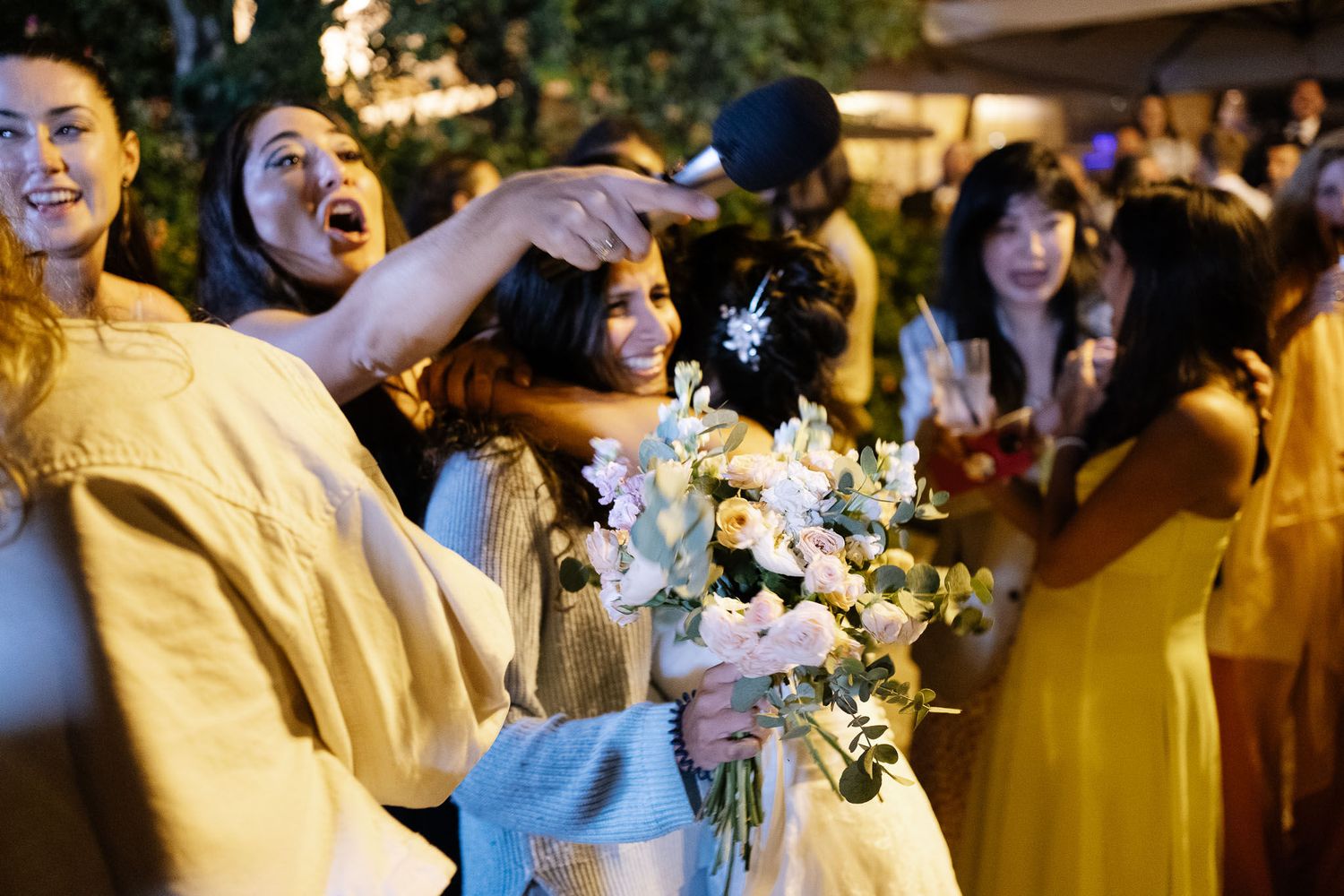 Party guests celebrate with sparklers and flowers during nighttime outdoor event.