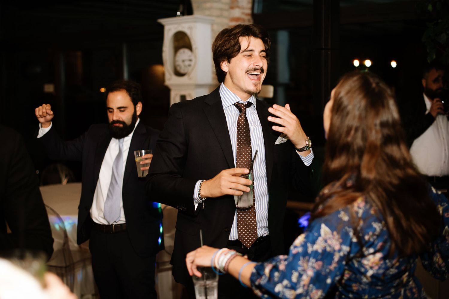 Party guests laughing and socializing during evening celebration event.
