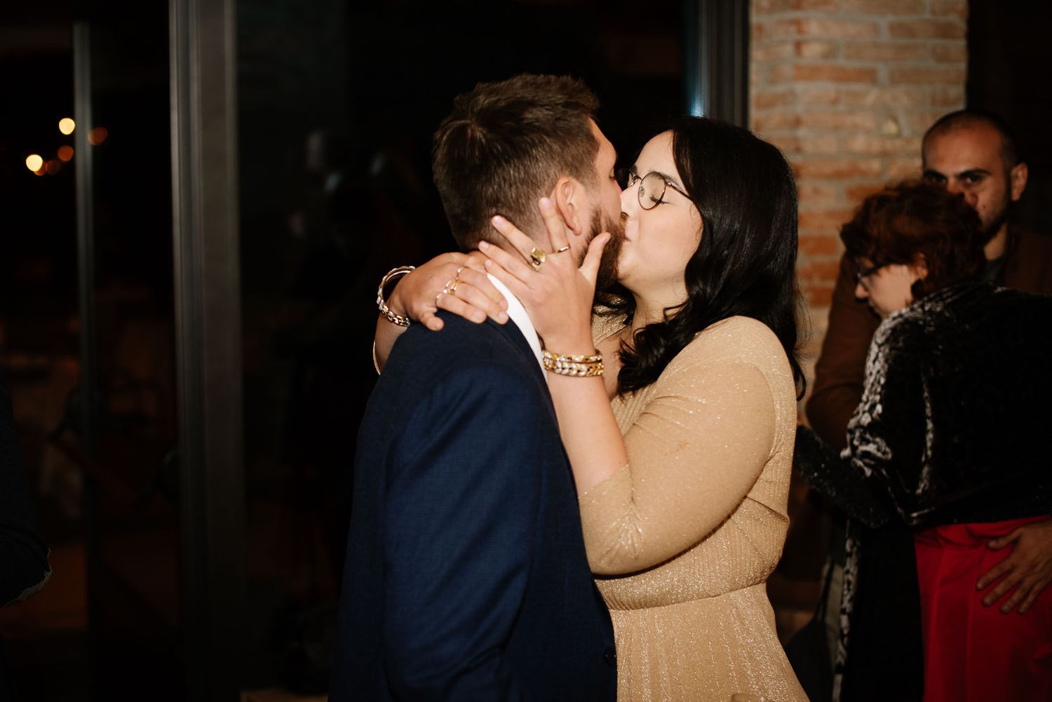 A couple shares a romantic moment in formal attire at an evening celebration.