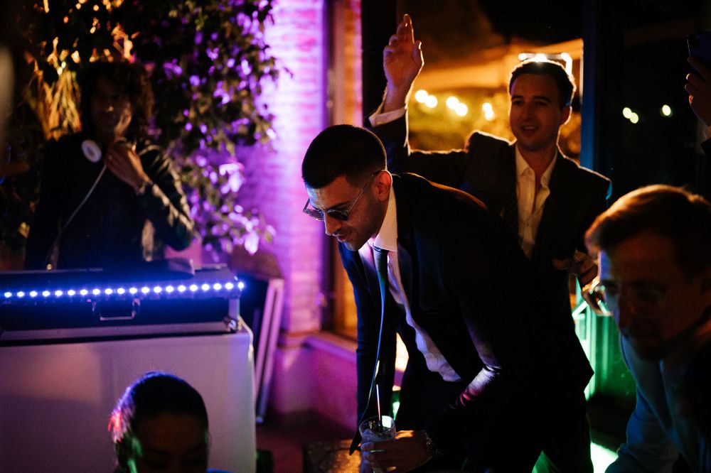 Partygoers raise their hands and dance under ambient lighting at a nighttime celebration.