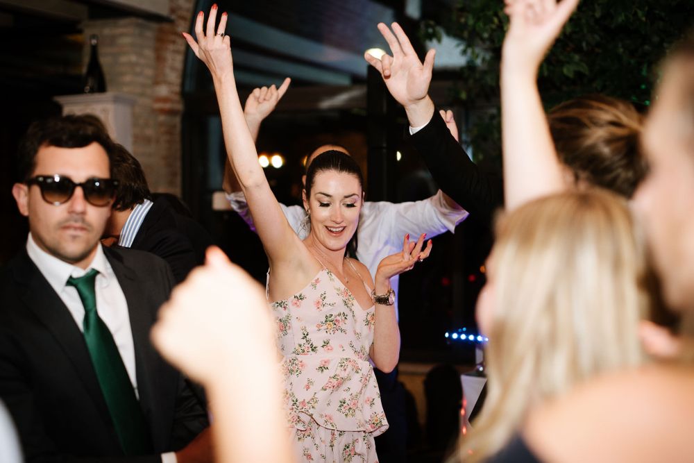 Party guests dancing with raised arms on a festively lit dance floor.