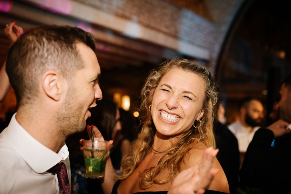 Party guests sharing laughter and drinks during an evening celebration.