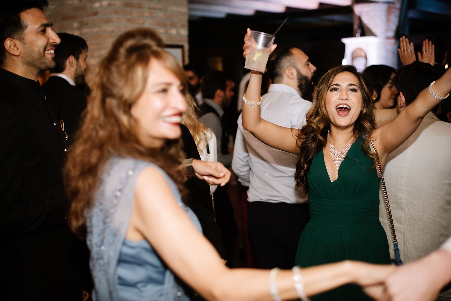 Celebration scene with partygoers dancing joyfully in formal attire at an indoor event.