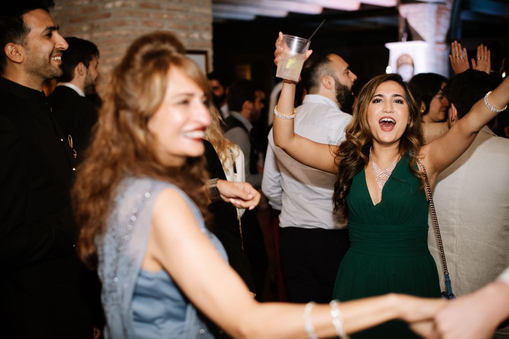 Celebration scene with partygoers dancing joyfully in formal attire at an indoor event.