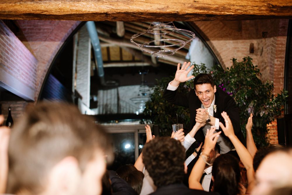 Crowd celebrating beneath wooden beams at an indoor party venue.