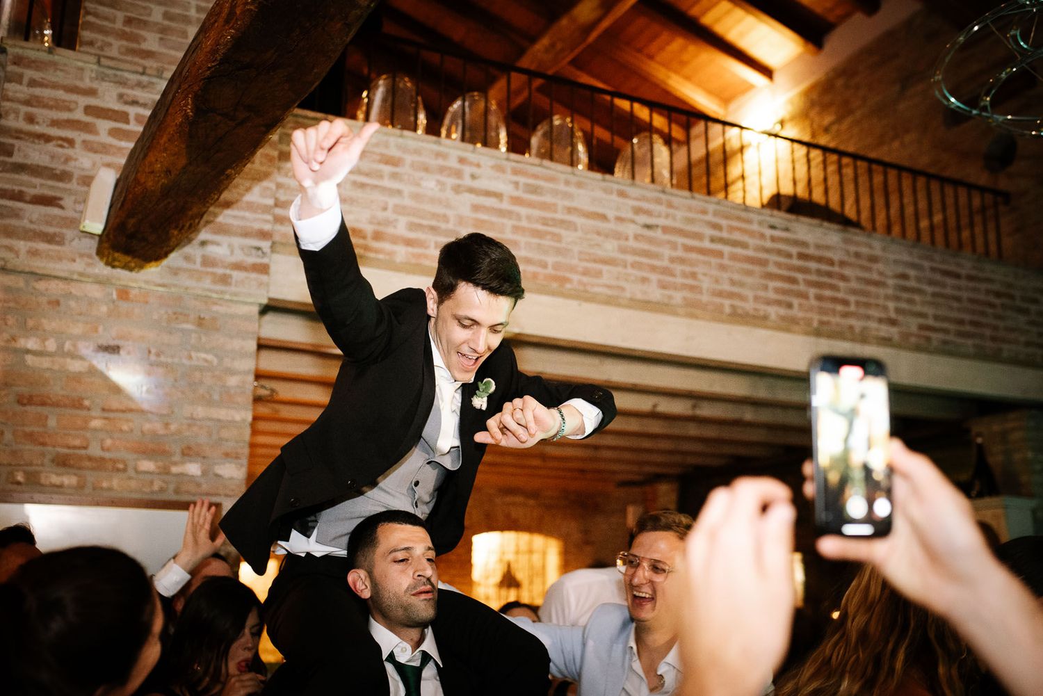 Celebratory moment with guest being hoisted on shoulders during indoor reception.