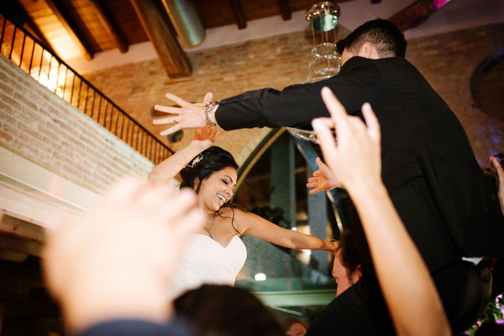 Guests celebrating and reaching up during lively indoor wedding reception.