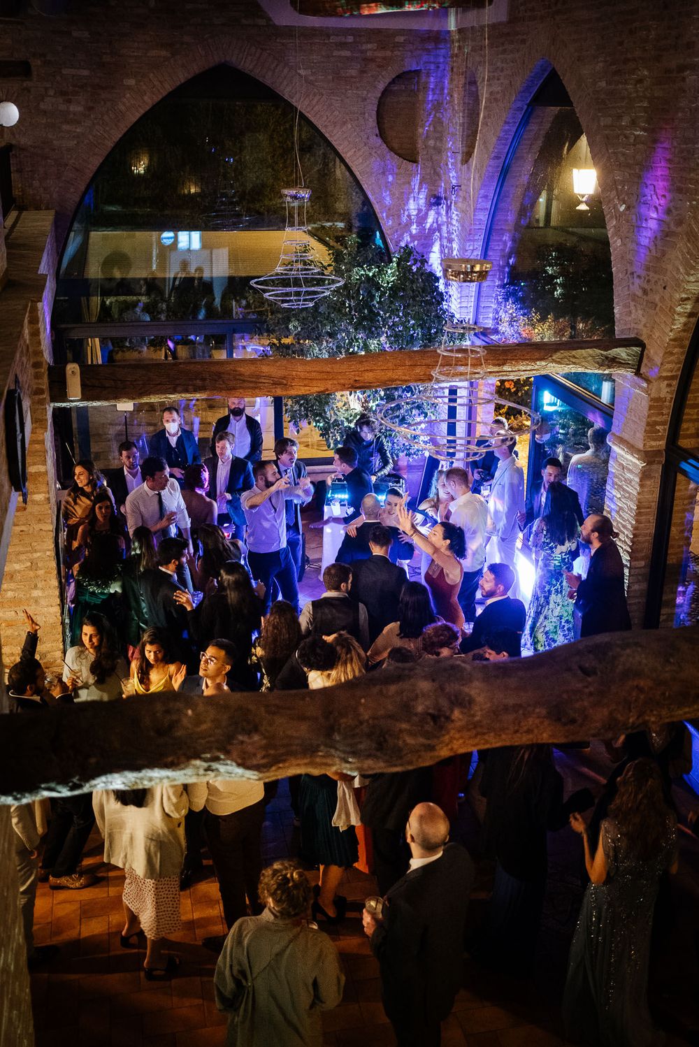 Wedding reception dance floor with blue lighting under arched brick architecture.