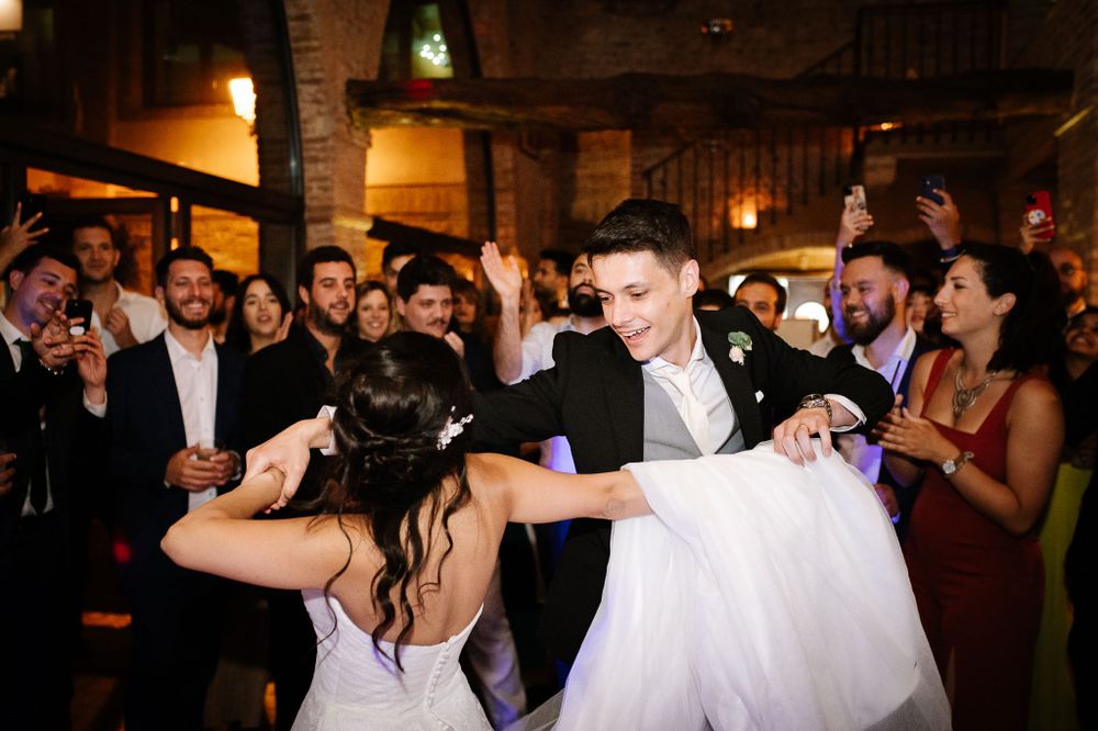 A couple performing a romantic dance move during their wedding reception surrounded by guests.