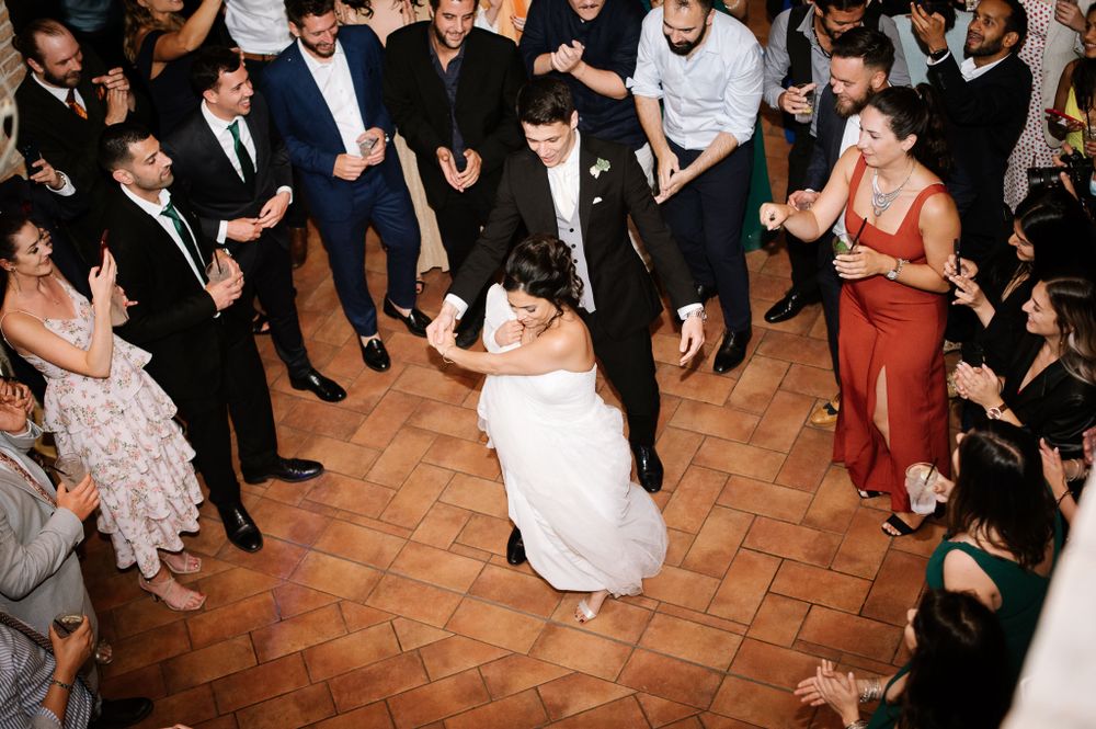 Wedding celebration on terracotta tiles with guests circled around the dancing couple.