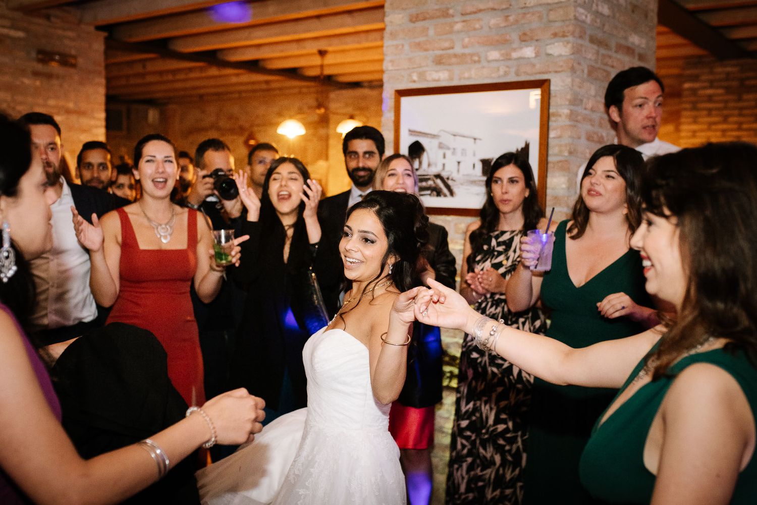 Wedding reception dance party with the bride in white dress surrounded by celebrating guests.