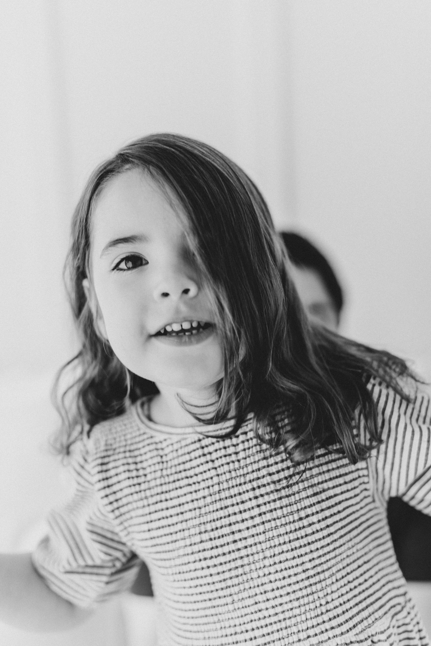 Black and white portrait of child laughing in striped shirt.