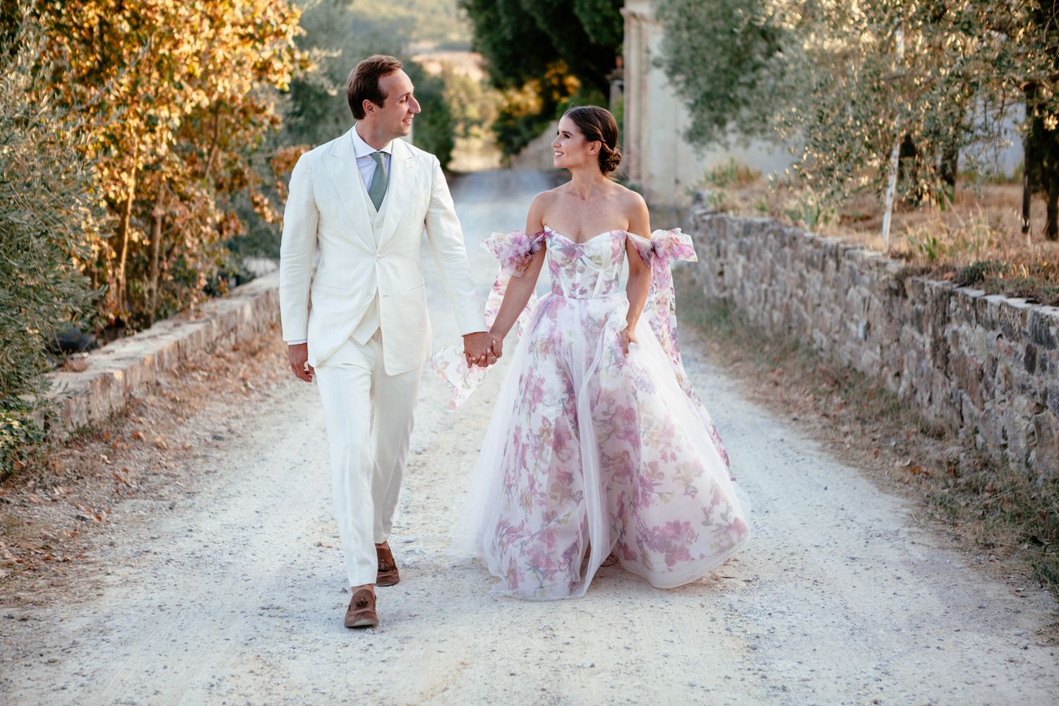 bride and groom walk down a white road with tuscan charm at their wedding in Chianti