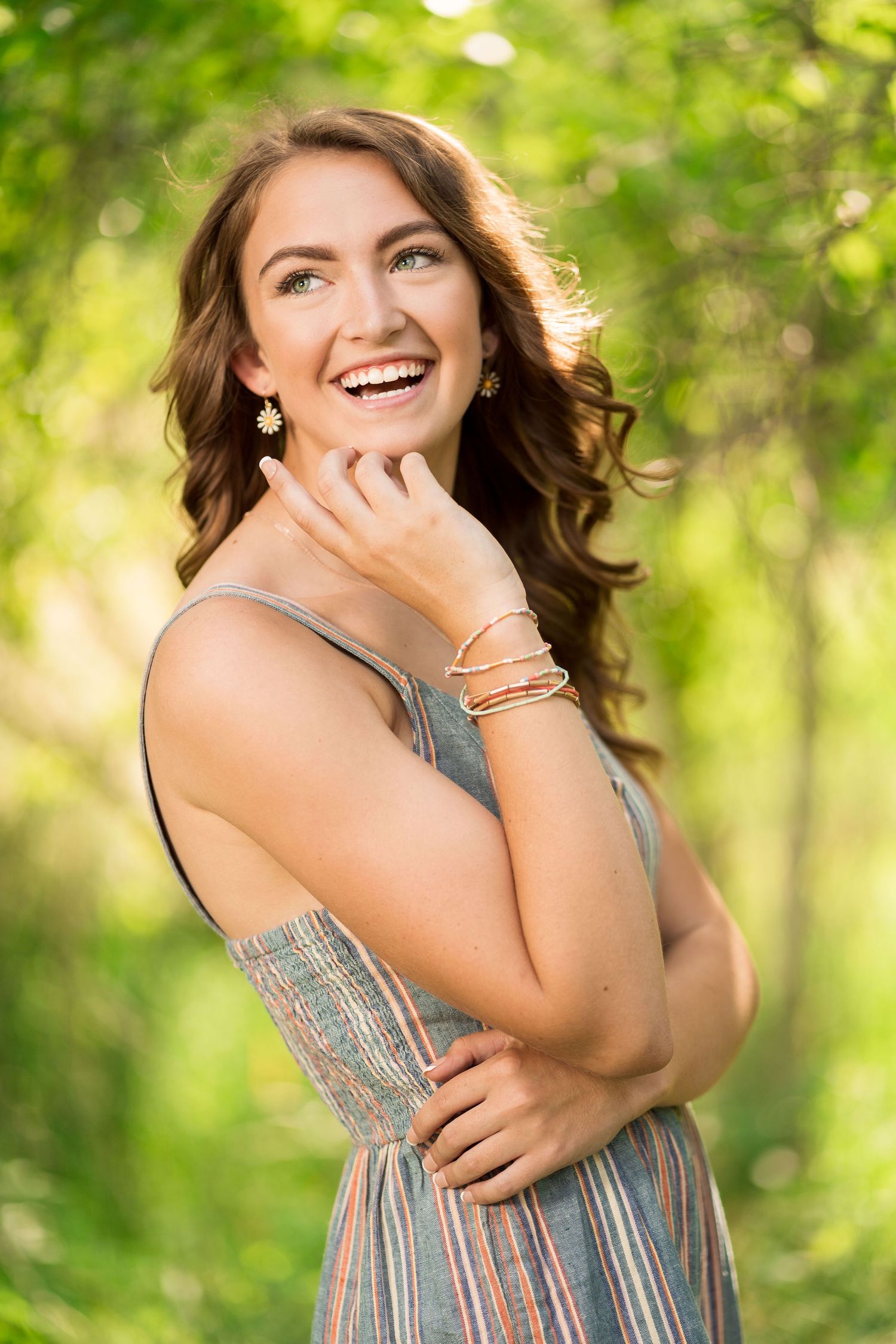 Joyful outdoor portrait session in striped dress with natural green background.