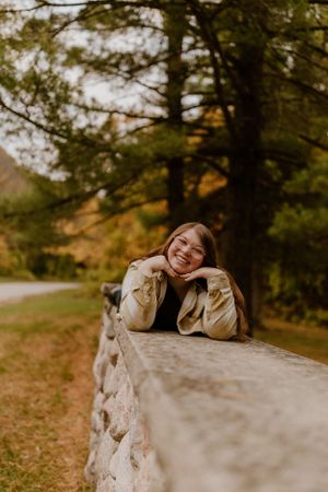Person resting on stone wall surrounded by autumn foliage.