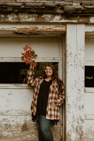 Person in plaid flannel jacket standing against weathered rustic building.