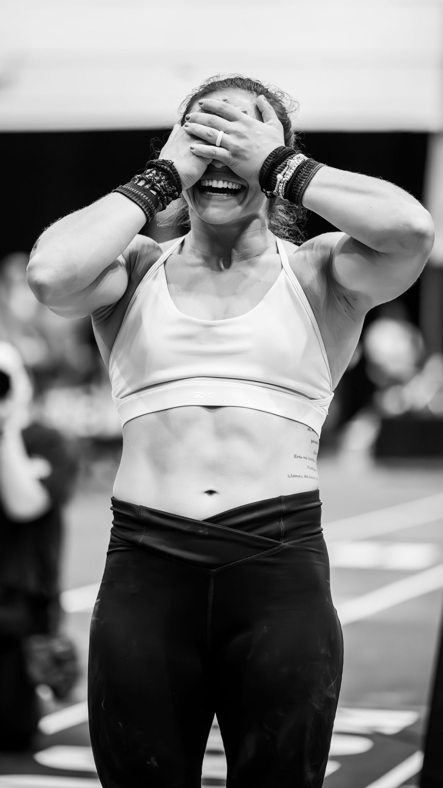 Exhausted athlete covering face with hands after intense workout competition.