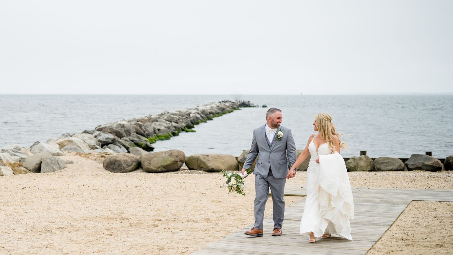 Happy couple strolling hand in hand along the beach.