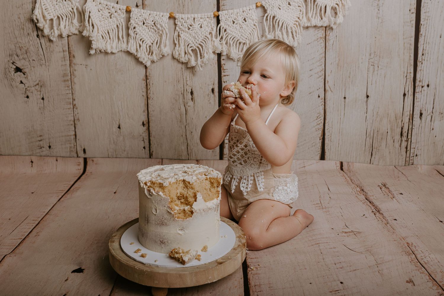 Cozy cake smash photography session featuring a simple white cake against distressed wood paneling.