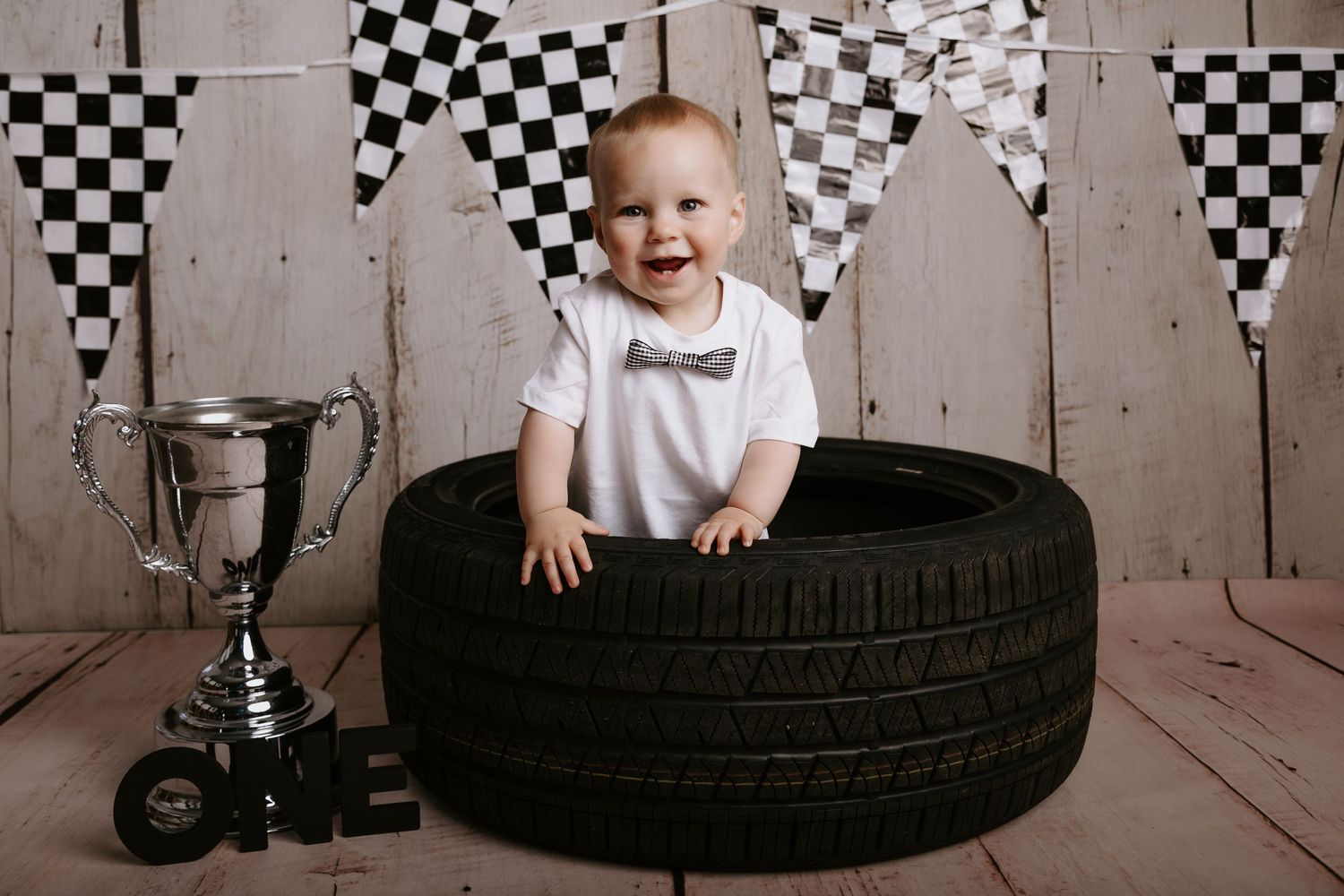 Automotive themed birthday scene with tire props and black and white checkered flag backdrop.