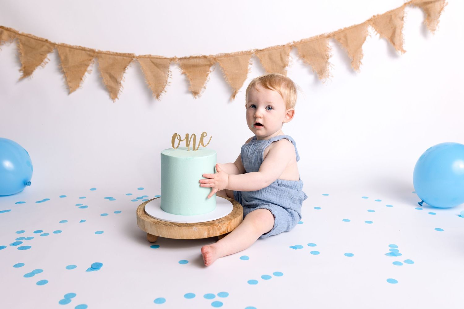 First birthday cake smash photos with blue accents and burlap bunting decoration.