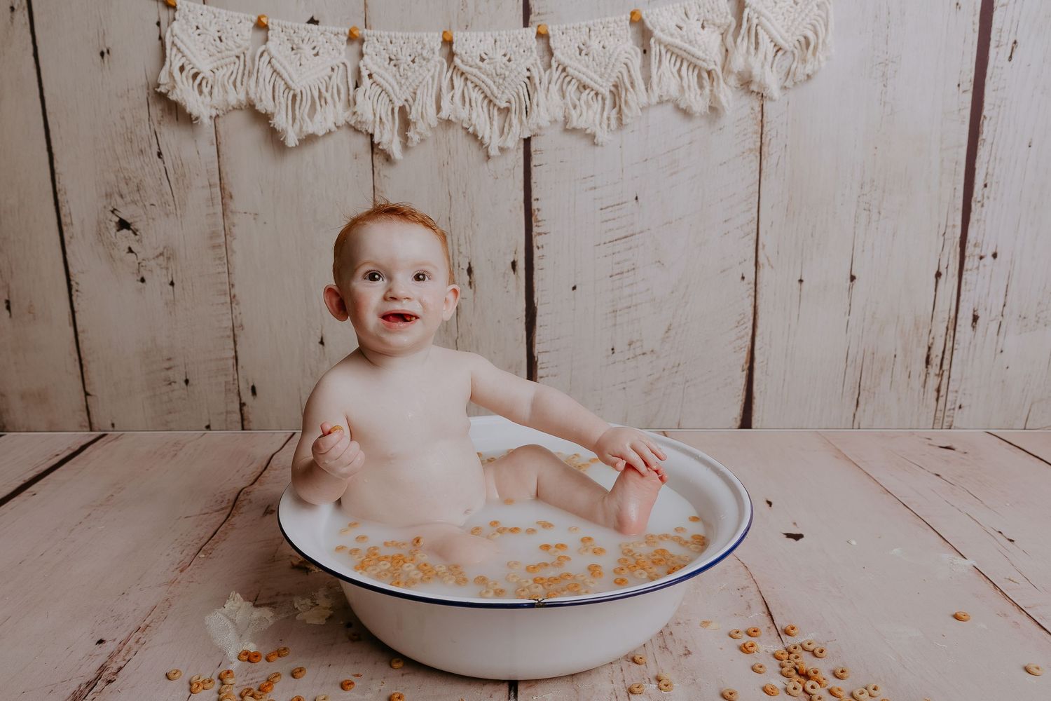 Baby playing in bath of milk and cereal during creative photo session.