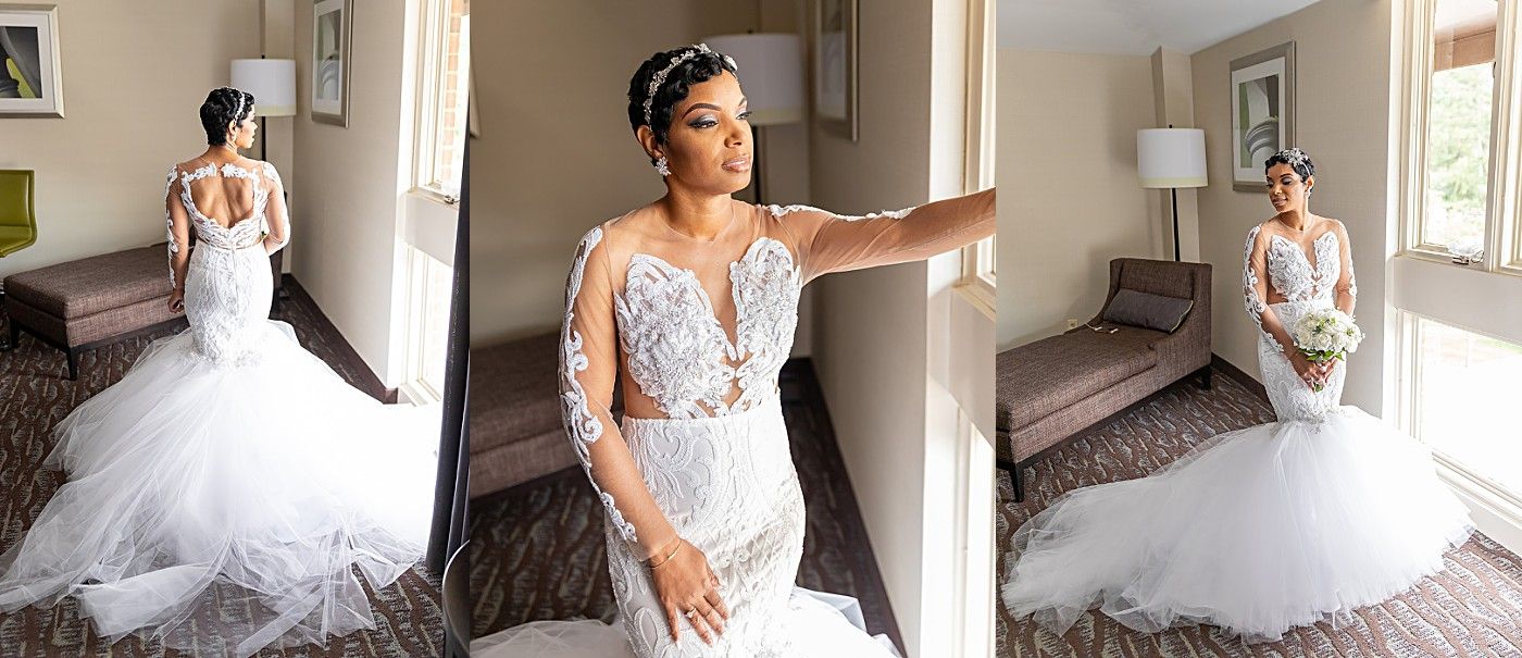 Stunning bride in long-sleeve lace mermaid wedding gown posing in hotel room before ceremony.