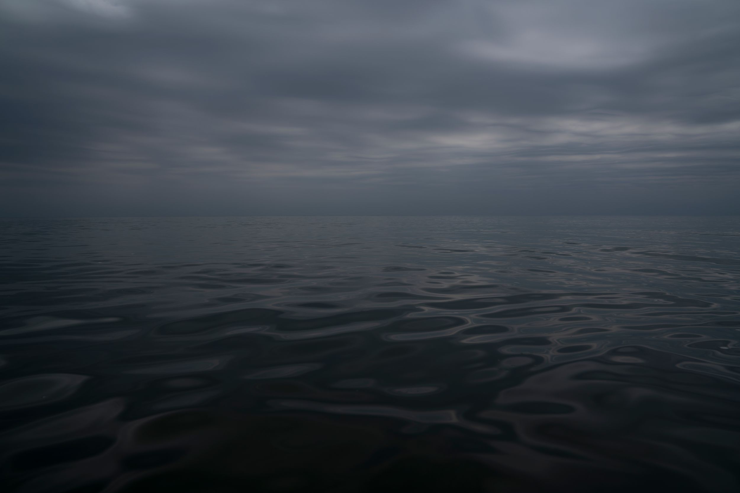 Dark moody seascape with rippling water under cloudy gray skies.