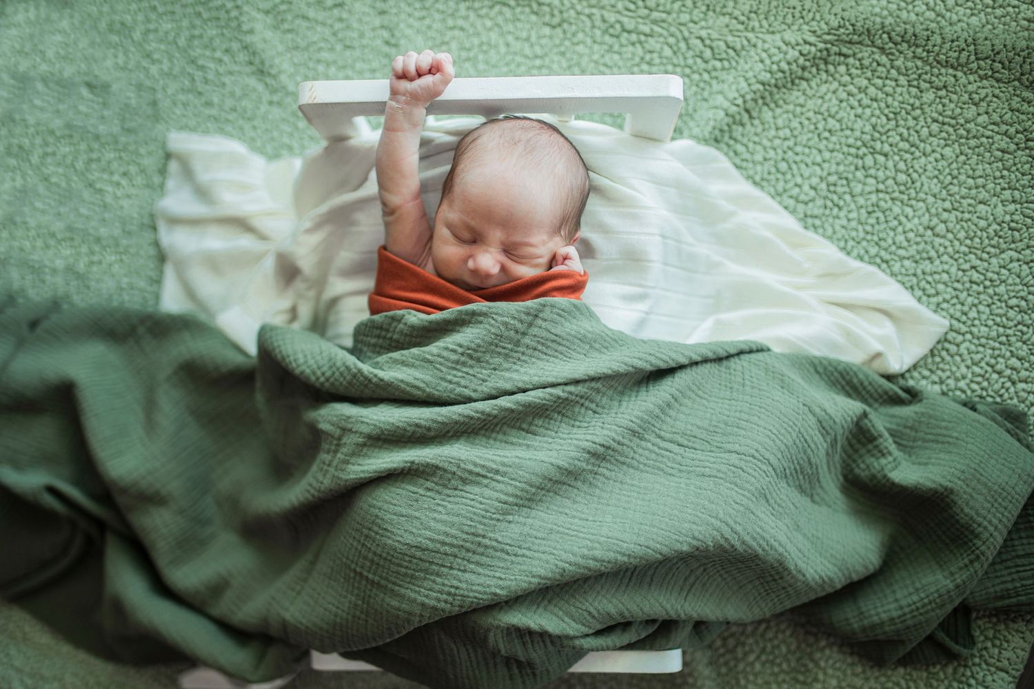 Sleeping newborn wrapped in soft mint green blankets during professional photo session.