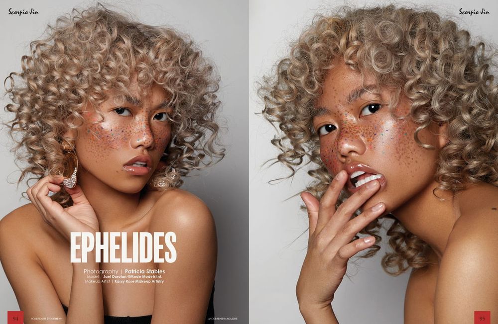 Editorial fashion portrait with blonde curly hair against gray background.