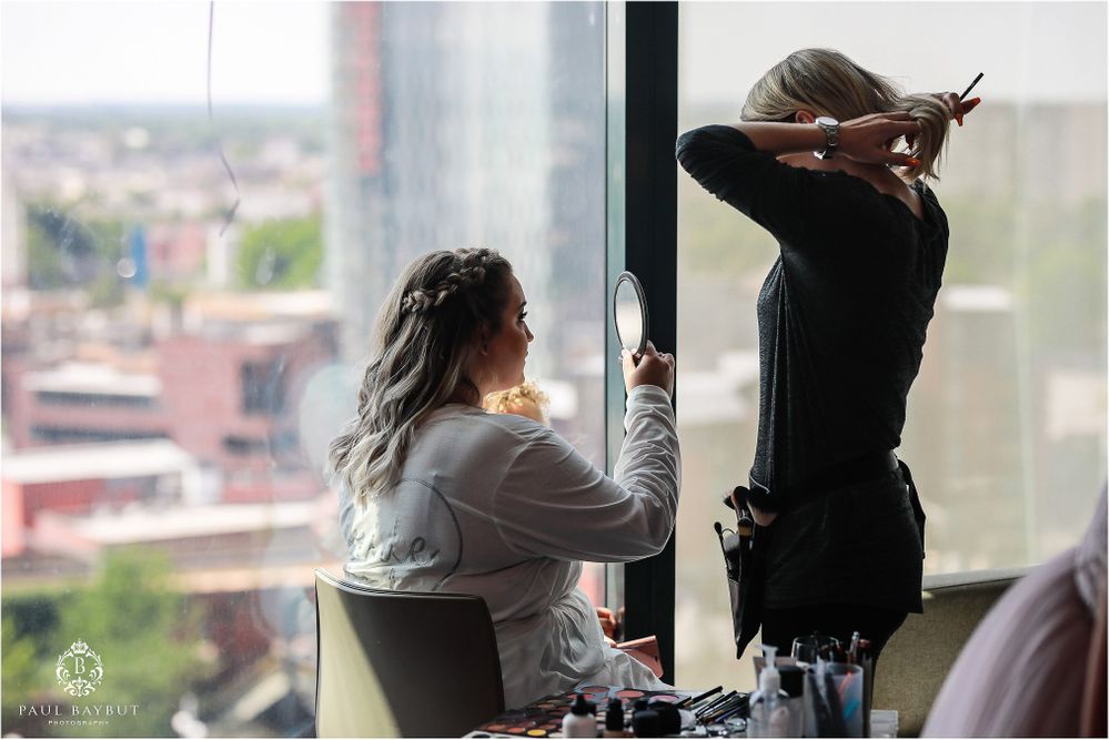 Two people working on wedding preparations near large window with city view.