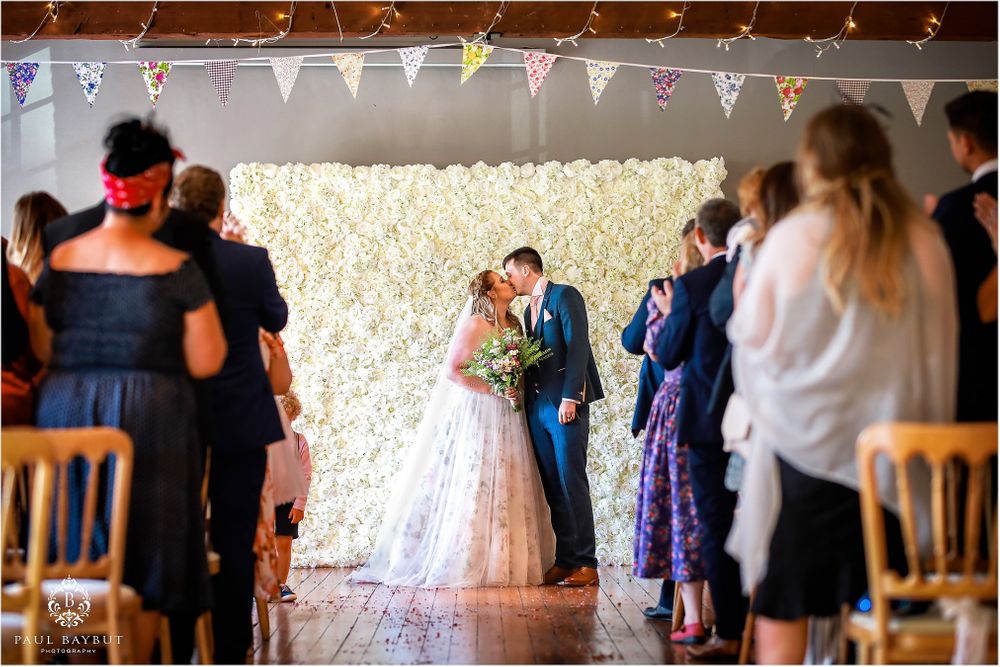 Wedding ceremony setup with white bunting and string lights decorating a rustic venue.