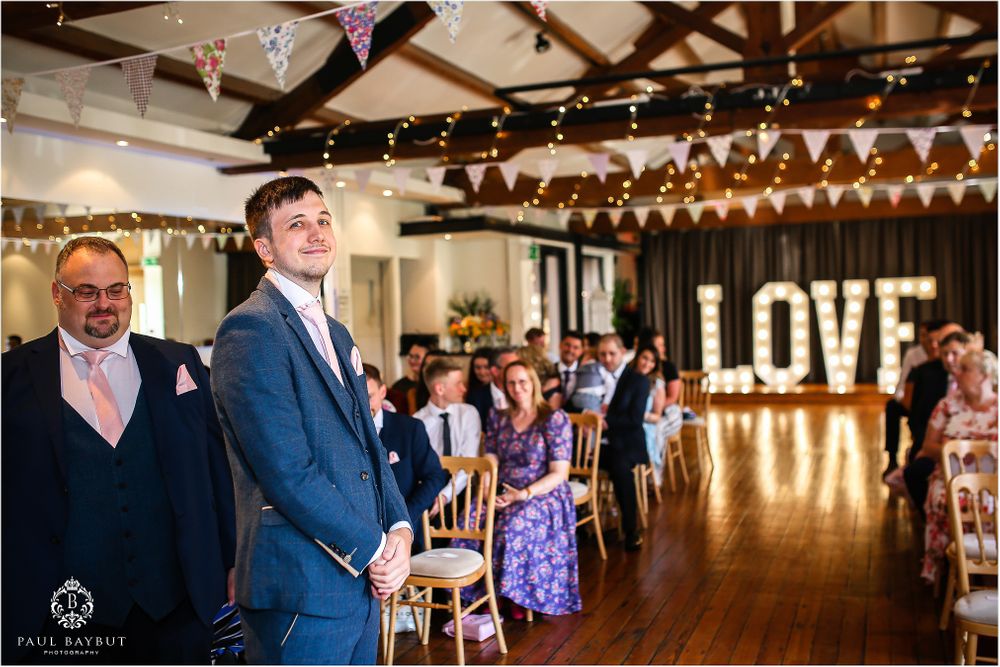 Wedding reception venue with wooden beams, string lights and illuminated LOVE sign.
