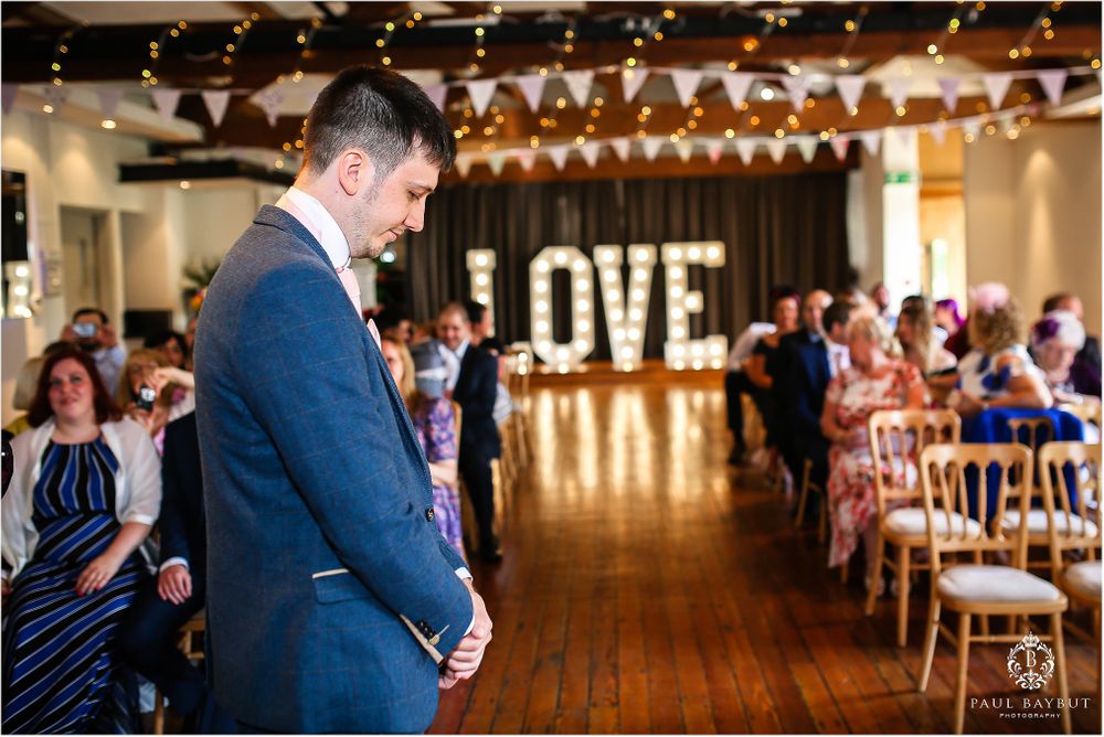 Wedding venue interior with rustic wooden floors and illuminated LOVE sign.